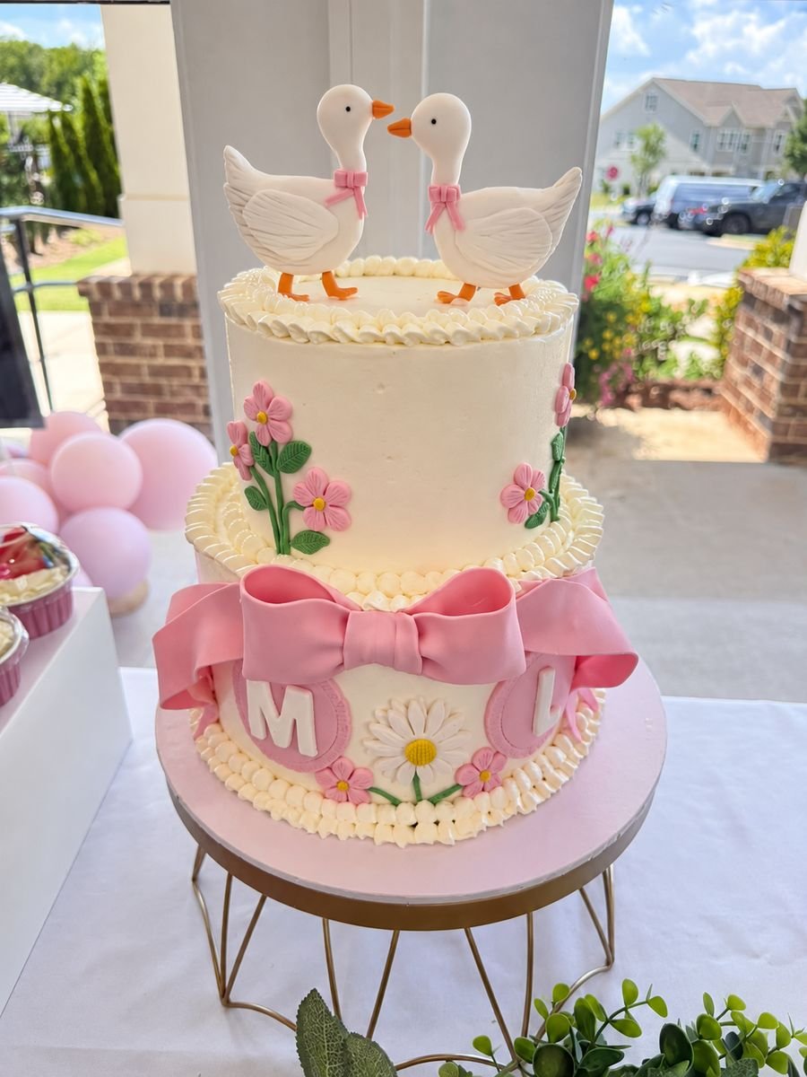 Pink baby shower cake with fondant ducks, bow and daisies